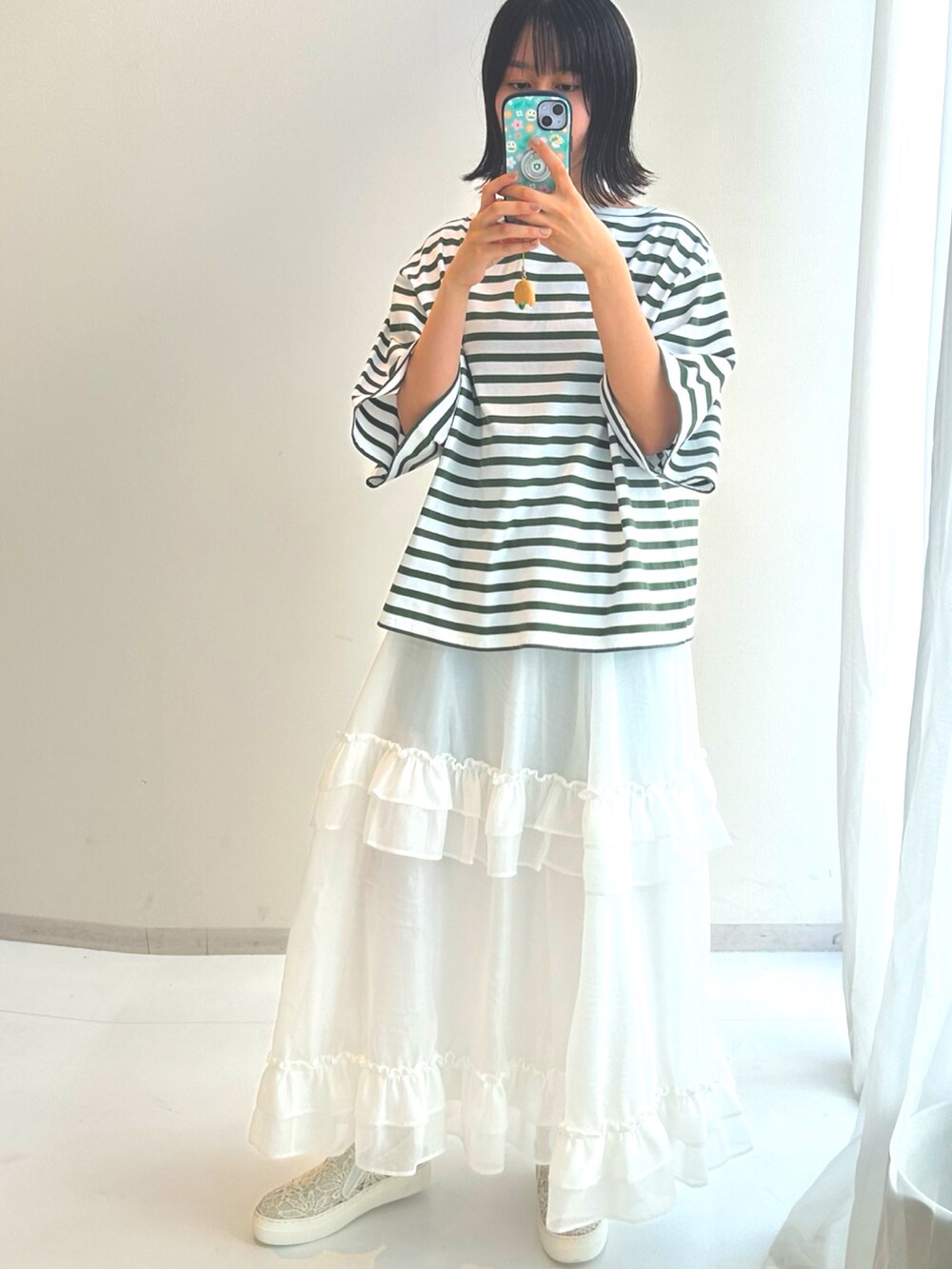 ホワイト系のTシャツ/カットソー、ホワイト系のスカート、ホワイト系のスニーカーを着用したレディースの秋コーディネートの2枚目の写真