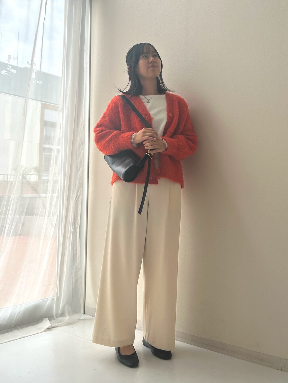 オレンジ系のカーディガン/ボレロ、ベージュ系のスラックス、ブラック系のバレエシューズを着用したレディースの秋コーディネートの3枚目の写真