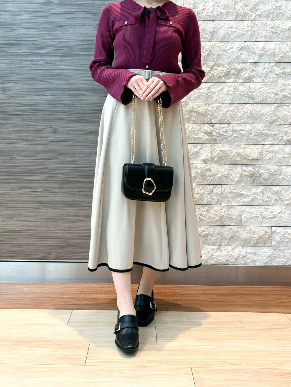 パープル系のニット/セーター、ベージュ系のスカート、ブラック系のパンプスを着用したレディースの冬コーディネートの2枚目の写真