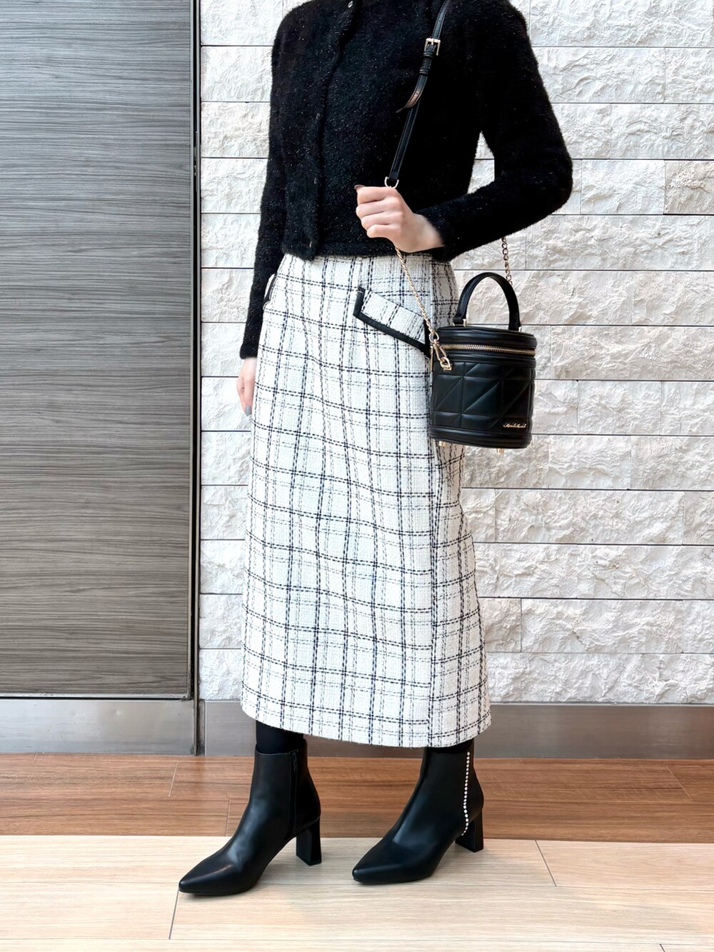 ホワイト系のスカート、グレー系のカーディガン/ボレロ、ブラック系のショルダーバッグを着用したレディースの冬コーディネートの2枚目の写真