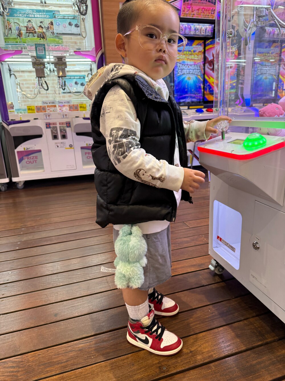 ホワイト系のパーカー、ブラック系のダウンベスト、グレー系のスウェットパンツを着用したキッズの秋コーディネートの2枚目の写真