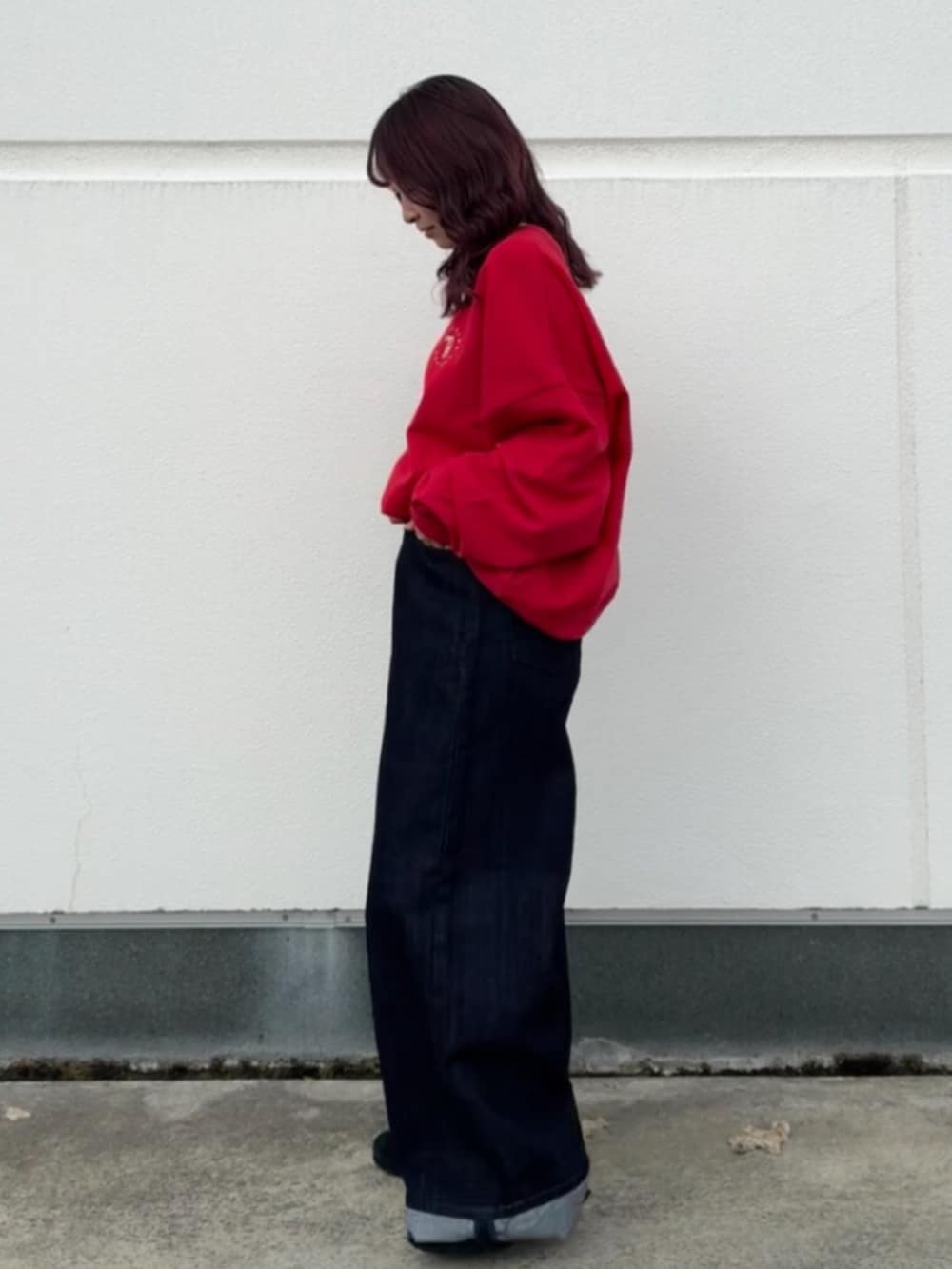 レッド系のスウェット、ブルー系のデニムパンツを着用したレディースの秋コーディネートの2枚目の写真