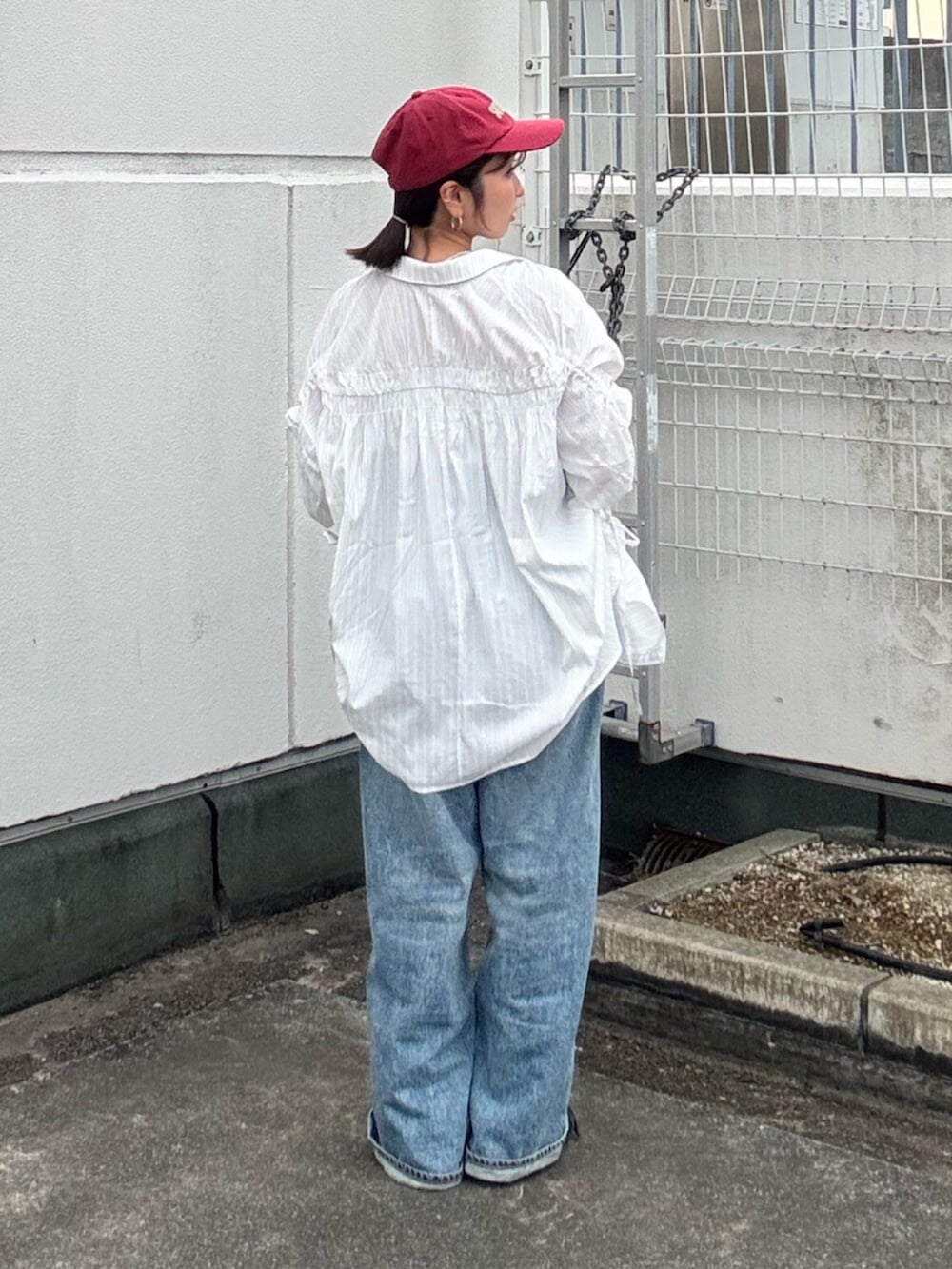 ブルー系のデニムパンツ、ホワイト系のシャツ/ブラウス、レッド系のキャップを着用したレディースの冬コーディネートの3枚目の写真