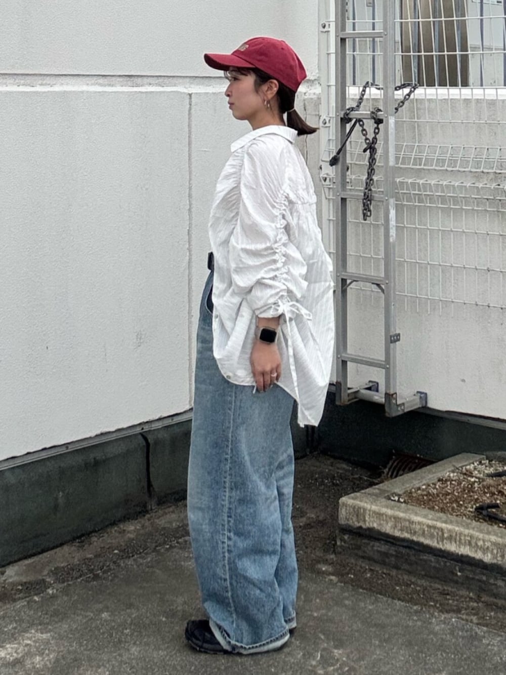 ブルー系のデニムパンツ、ホワイト系のシャツ/ブラウス、レッド系のキャップを着用したレディースの冬コーディネートの2枚目の写真