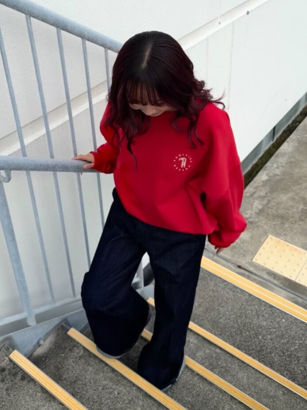 レッド系のスウェット、ブルー系のデニムパンツを着用したレディースの秋コーディネートの5枚目の写真