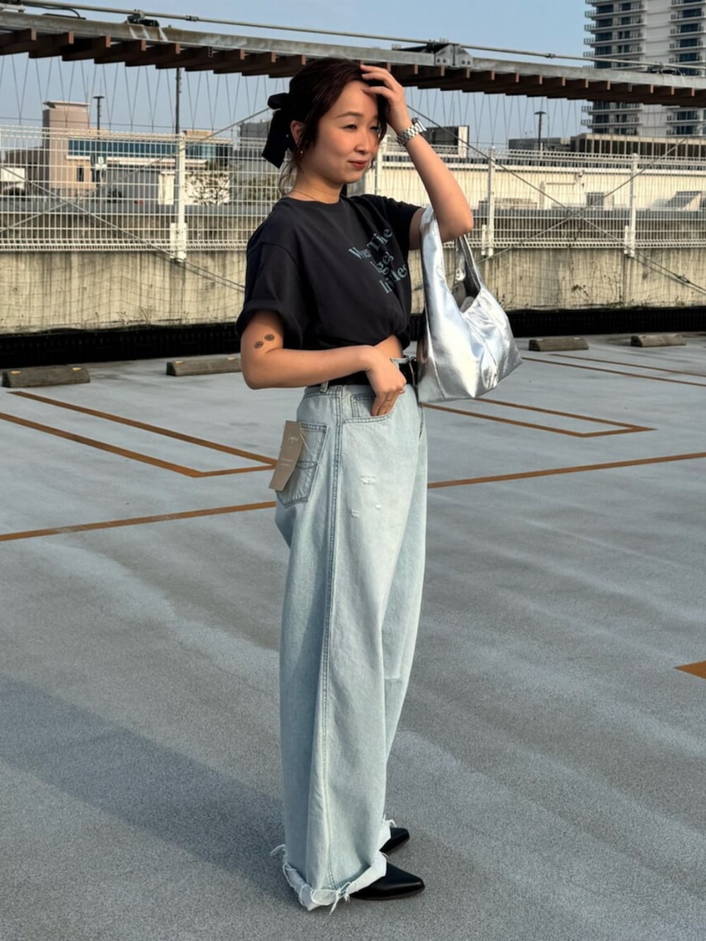 グレー系のTシャツ/カットソー、ブルー系のデニムパンツ、シルバー系のハンドバッグを着用したレディースの春コーディネートの3枚目の写真