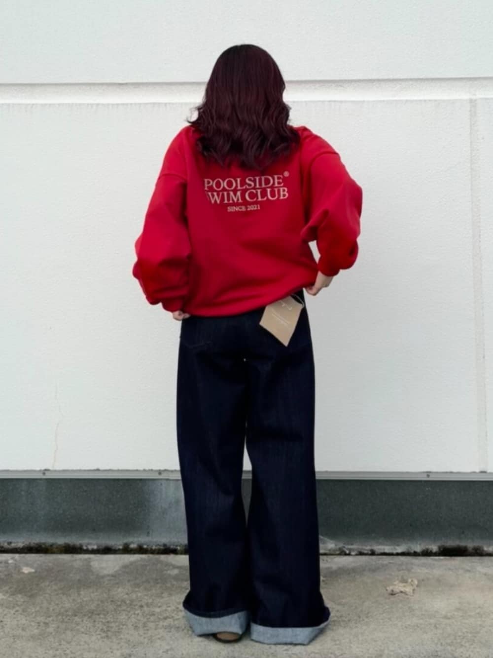 レッド系のスウェット、ブルー系のデニムパンツを着用したレディースの秋コーディネートの3枚目の写真