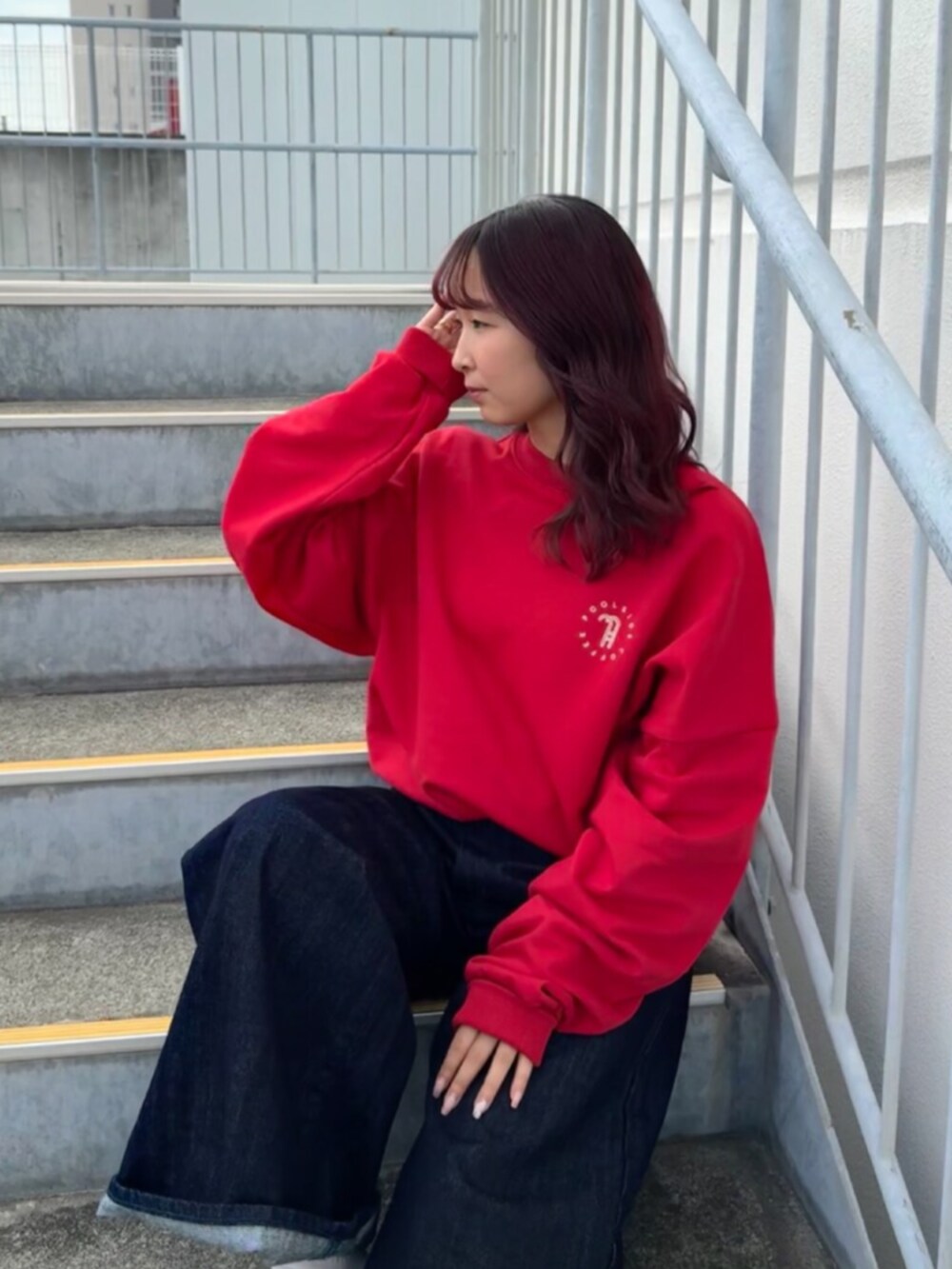 レッド系のスウェット、ブルー系のデニムパンツを着用したレディースの秋コーディネートの4枚目の写真