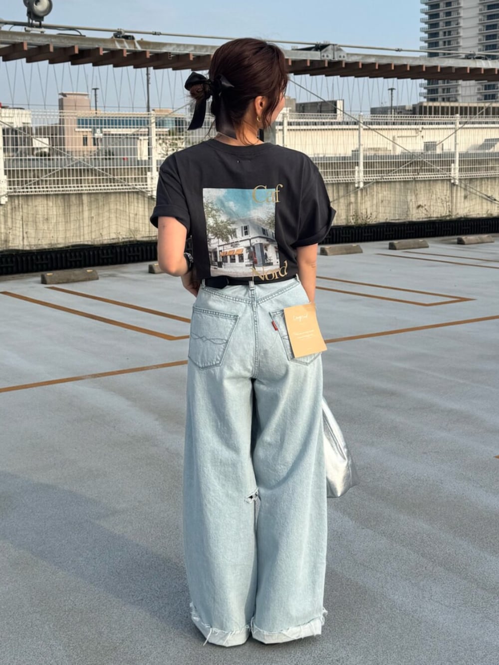 グレー系のTシャツ/カットソー、ブルー系のデニムパンツ、シルバー系のハンドバッグを着用したレディースの春コーディネートの2枚目の写真