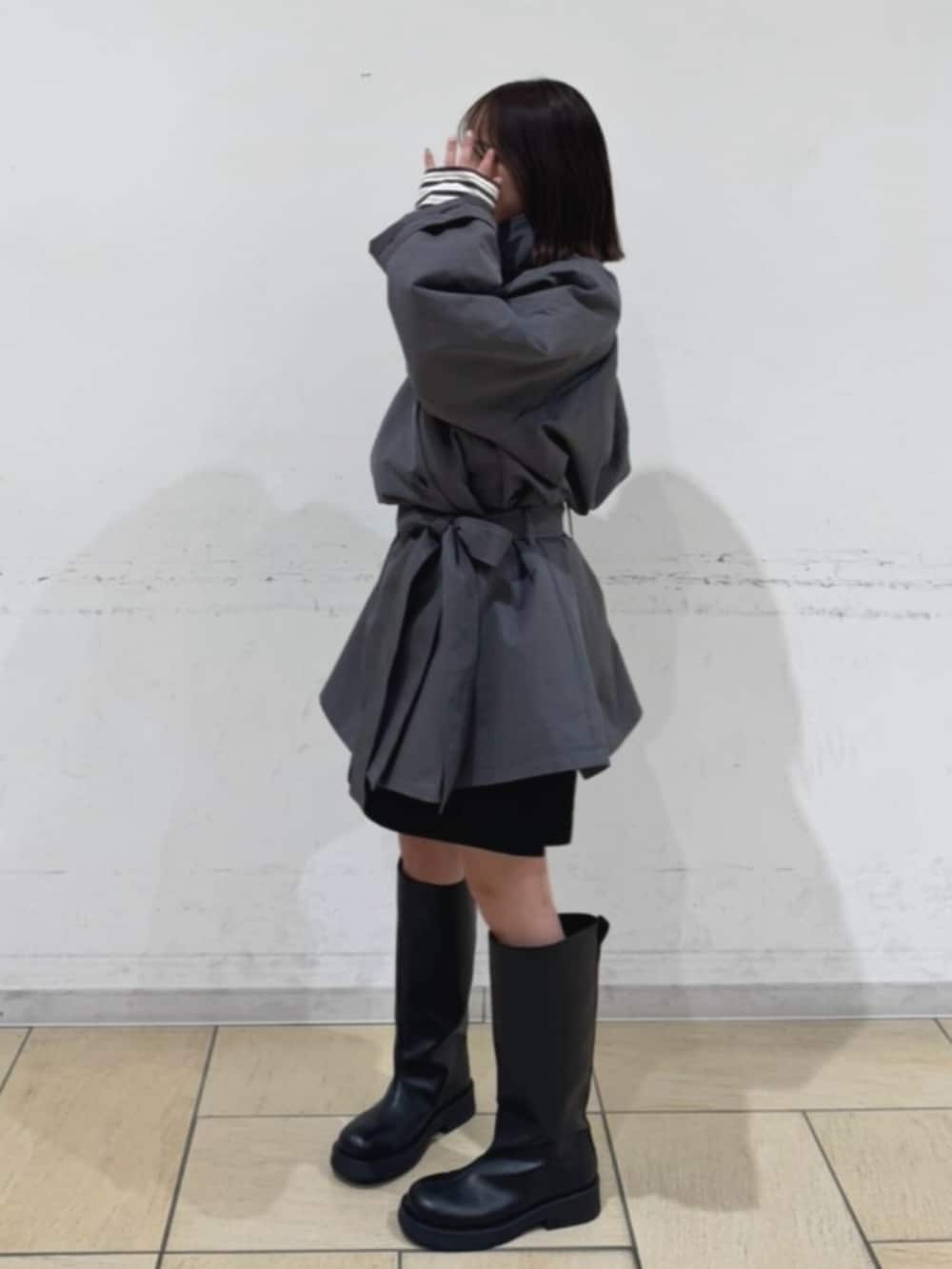 グレー系のトレンチコート、ブラック系のその他パンツ、ブラック系のブーツを着用したレディースの冬コーディネートの2枚目の写真