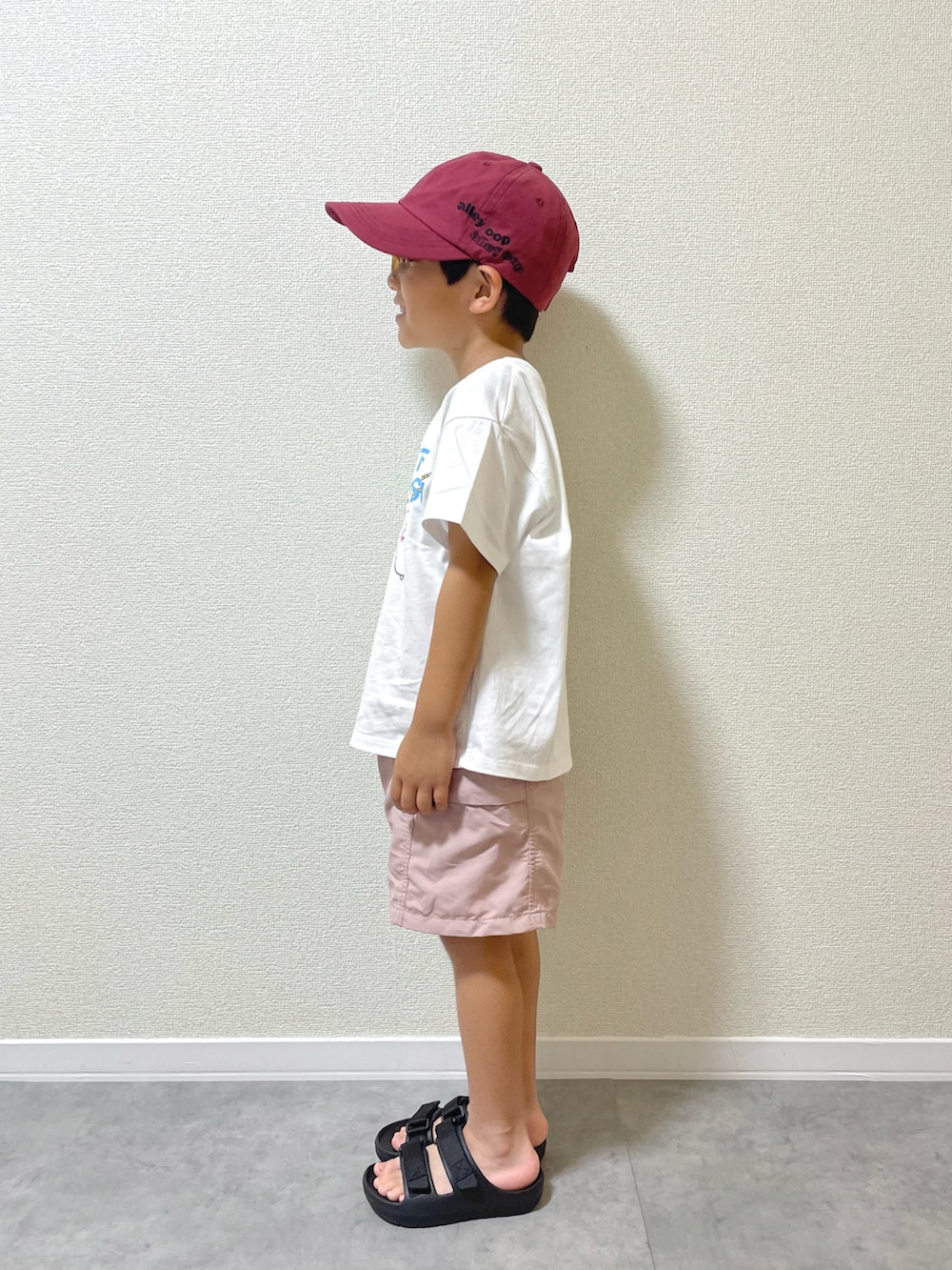 ホワイト系のTシャツ/カットソー、ブラック系のサンダル、レッド系のキャップを着用したキッズの夏コーディネートの3枚目の写真