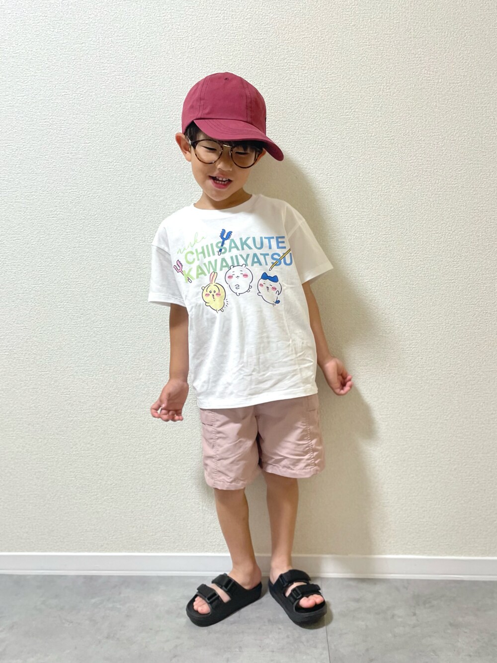 ホワイト系のTシャツ/カットソー、ブラック系のサンダル、レッド系のキャップを着用したキッズの夏コーディネートの2枚目の写真