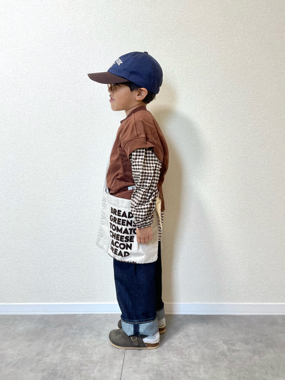 ブラウン系のスウェット、ベージュ系のショルダーバッグ、ブルー系のデニムパンツを着用したキッズの冬コーディネートの2枚目の写真