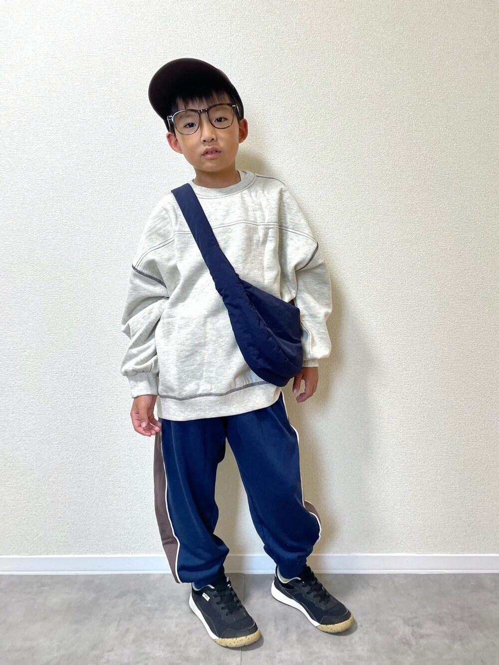 ベージュ系のスウェット、ブルー系のスウェットパンツ、ブルー系のショルダーバッグを着用したキッズの秋コーディネートの2枚目の写真