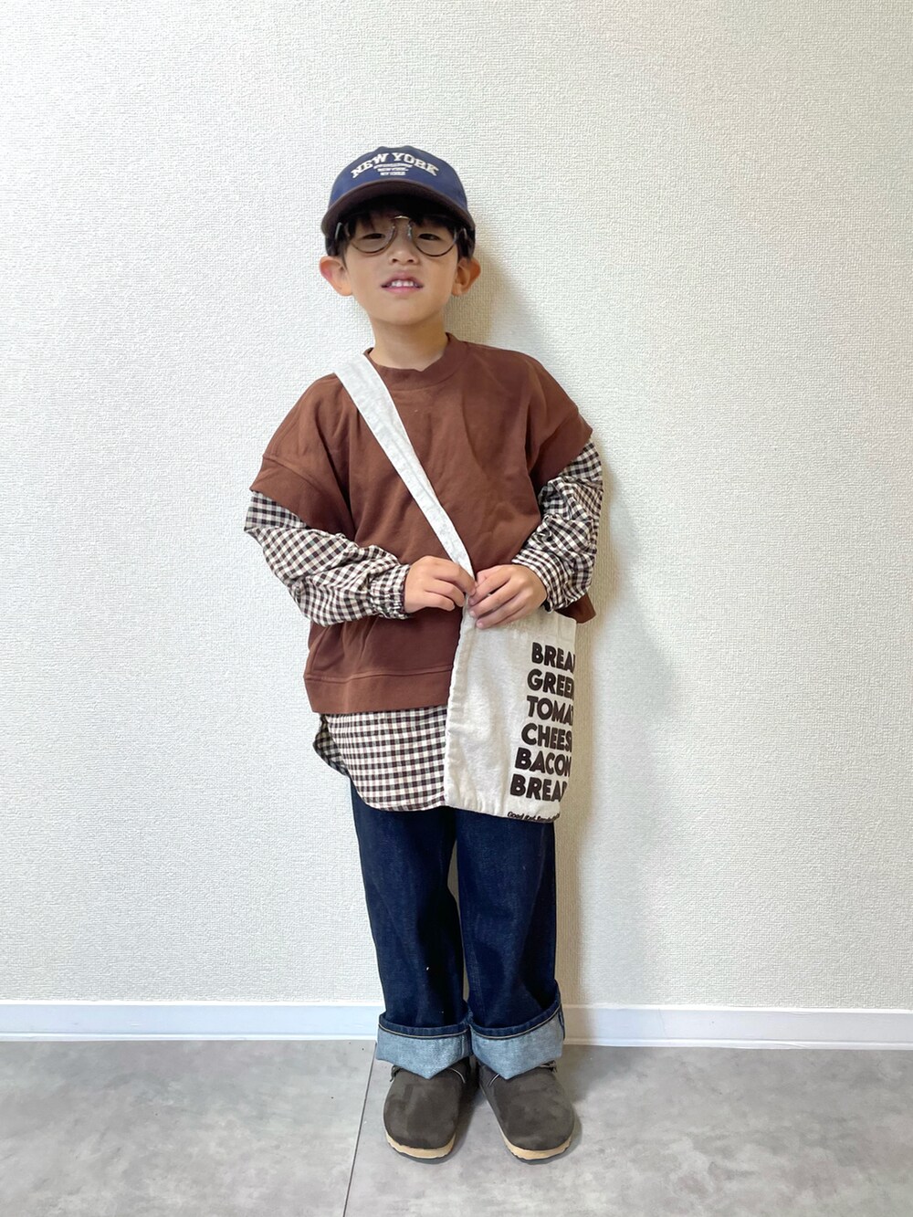 ブラウン系のスウェット、ベージュ系のショルダーバッグ、ブルー系のデニムパンツを着用したキッズの冬コーディネートの3枚目の写真