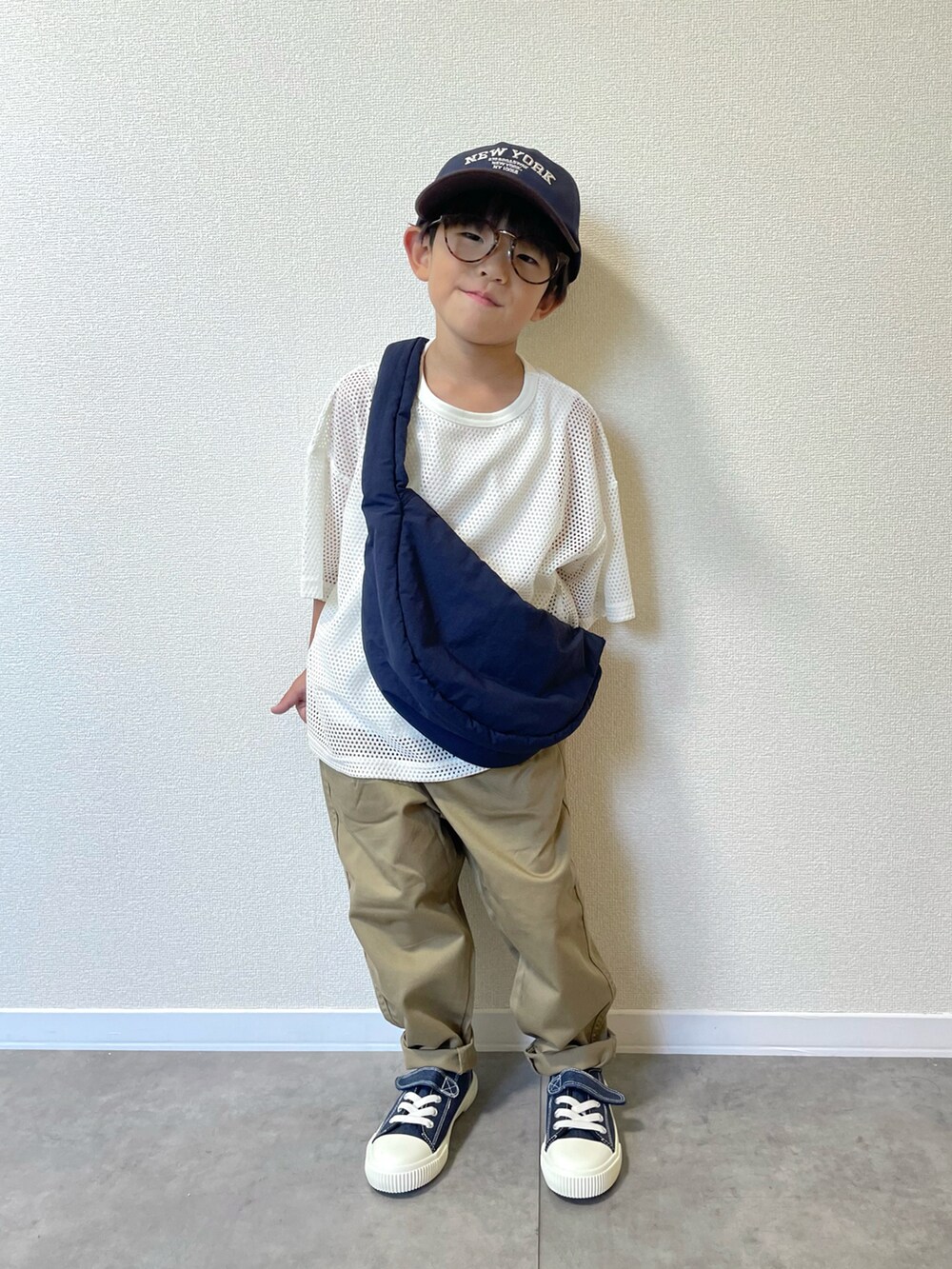 ブルー系のショルダーバッグ、ホワイト系のトップス、ベージュ系のチノパンツを着用したキッズの夏コーディネートの3枚目の写真