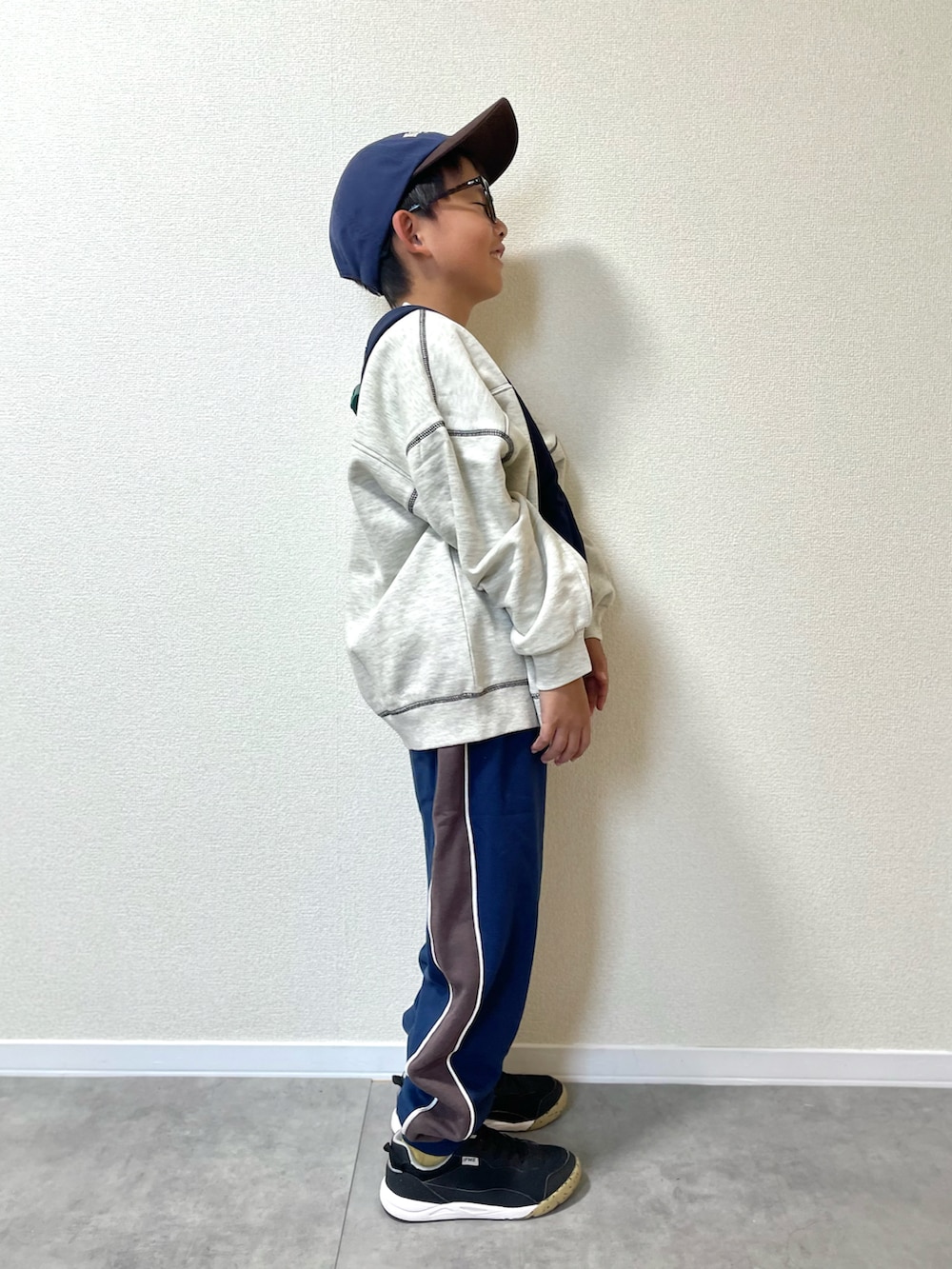 ベージュ系のスウェット、ブルー系のスウェットパンツ、ブルー系のショルダーバッグを着用したキッズの秋コーディネートの3枚目の写真