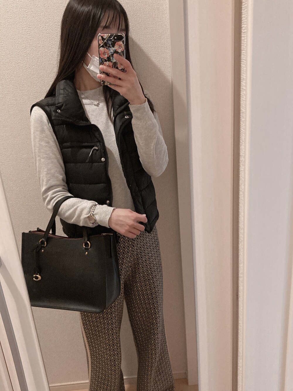 ブラック系のトートバッグ、ブラック系のダウンベスト、ブラック系のその他パンツを着用したレディースの冬コーディネートの2枚目の写真