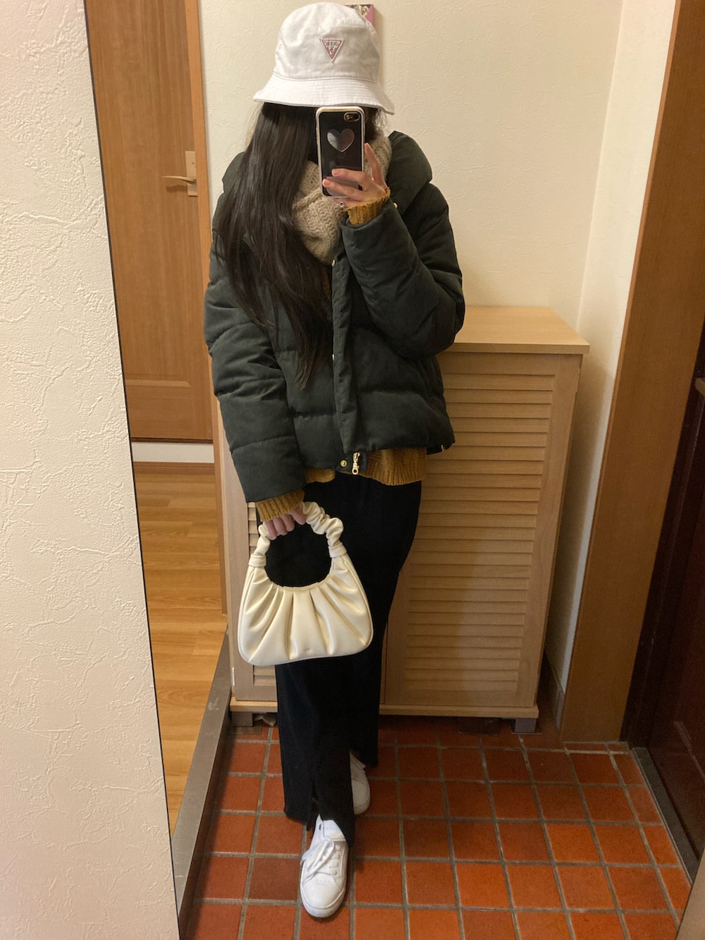 ブラック系のダウンジャケット/コート、オレンジ系のカーディガン/ボレロ、ブラック系のその他パンツを着用したレディースの春コーディネートの2枚目の写真