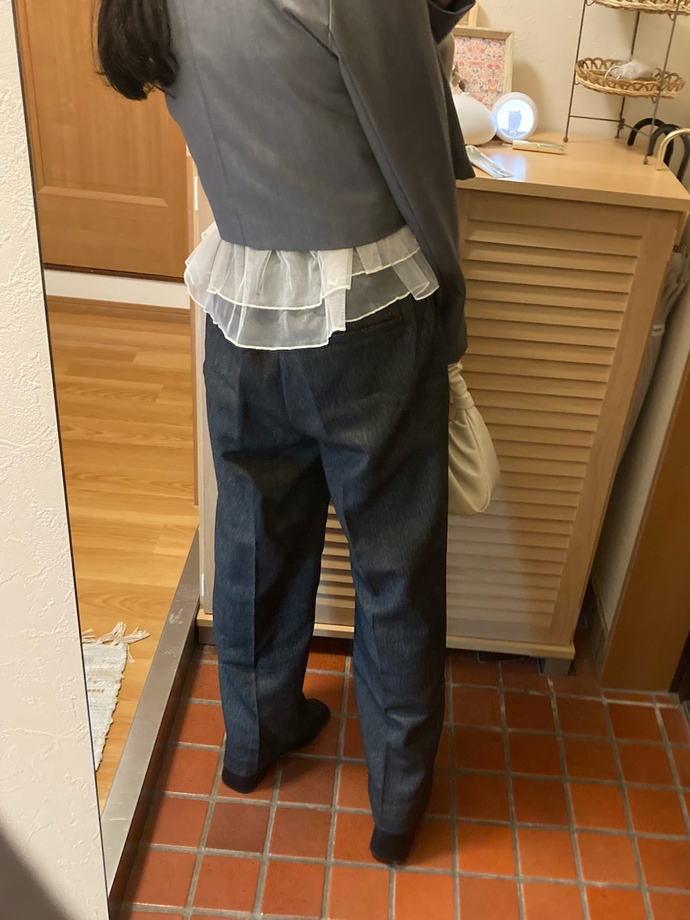 グレー系のスラックス、ホワイト系のハンドバッグ、ブラック系のブーツを着用したレディースの冬コーディネートの3枚目の写真