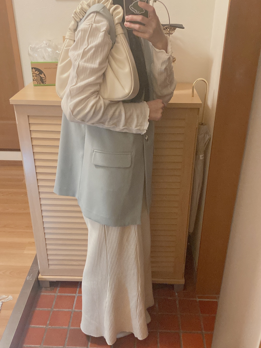 グリーン系のベスト、ホワイト系のTシャツ/カットソー、ホワイト系のハンドバッグを着用したレディースの秋コーディネートの2枚目の写真