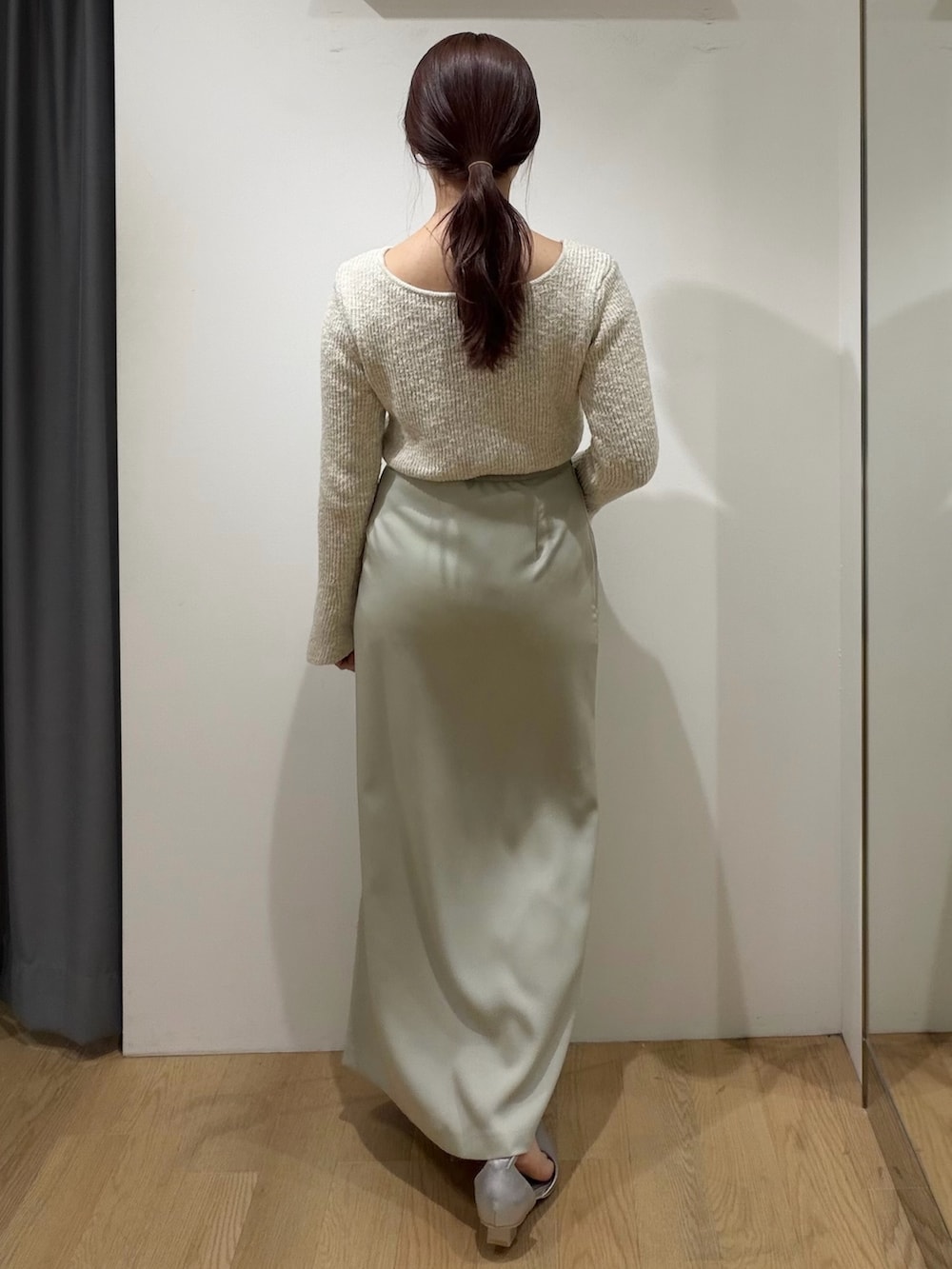 ベージュ系のニット/セーター、グリーン系のスカート、シルバー系のパンプスを着用したレディースの冬コーディネートの3枚目の写真