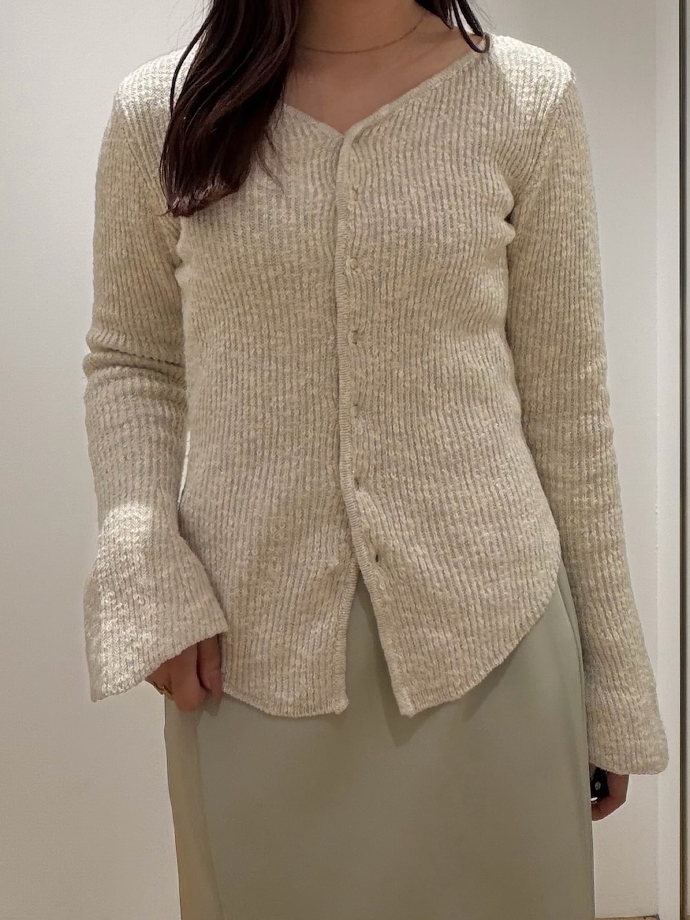 ベージュ系のニット/セーター、グリーン系のスカート、シルバー系のパンプスを着用したレディースの冬コーディネートの5枚目の写真