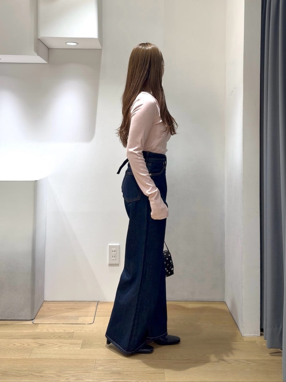 ピンク系のニット/セーター、ブルー系のデニムパンツ、ブラック系のブーツを着用したレディースの秋コーディネートの2枚目の写真