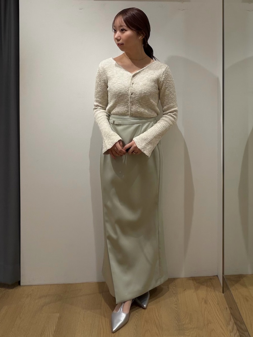 ベージュ系のニット/セーター、グリーン系のスカート、シルバー系のパンプスを着用したレディースの冬コーディネートの2枚目の写真
