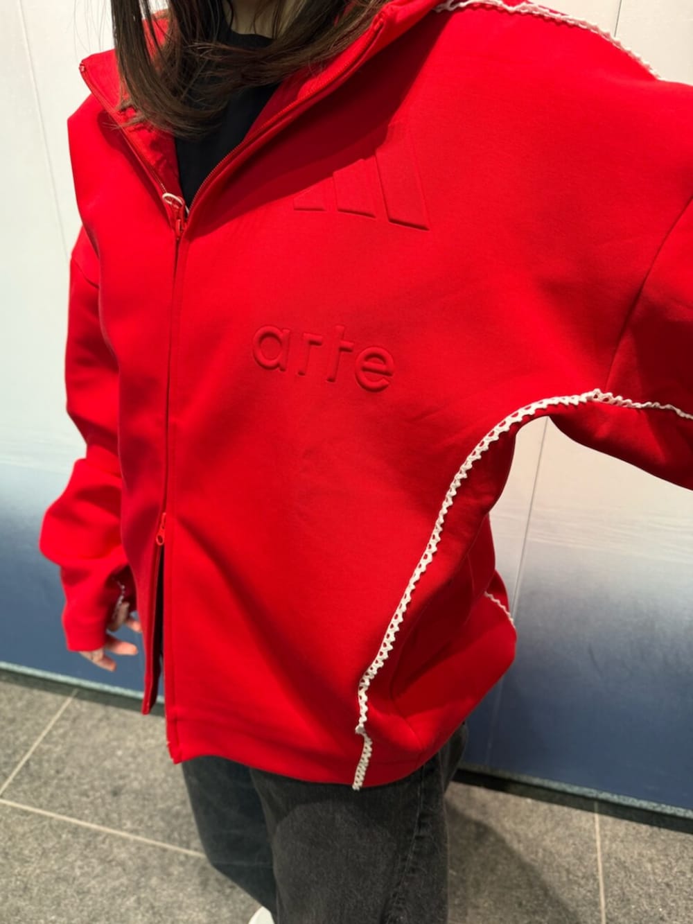 ホワイト系のスニーカー、レッド系のトップスを着用したレディースの冬コーディネートの3枚目の写真