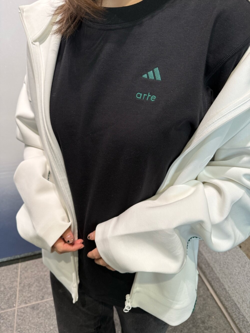 ホワイト系のトップス、ブラック系のトップス、ホワイト系のスニーカーを着用したレディースの冬コーディネートの3枚目の写真