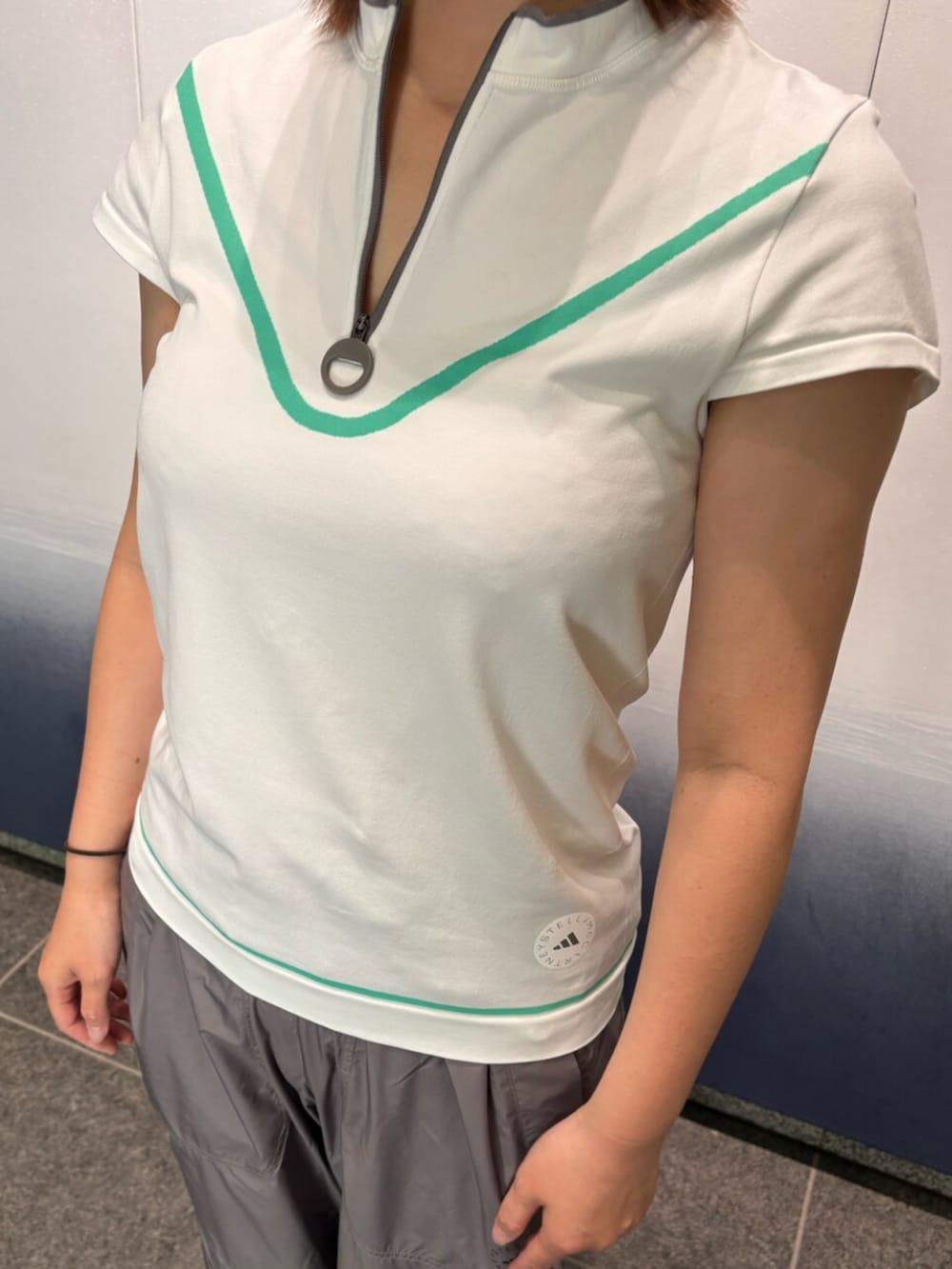 ホワイト系のTシャツ/カットソー、ブラック系のスニーカー、ベージュ系のサンバイザーを着用したレディースの夏コーディネートの2枚目の写真