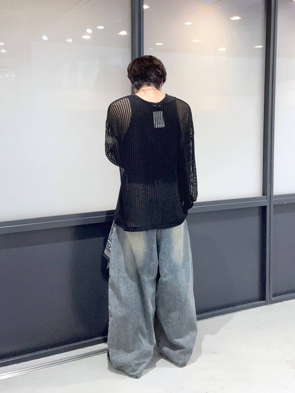 ブルー系のデニムパンツ、ブラック系のニット/セーター、グレー系のストール/ショールを着用したメンズの夏コーディネートの3枚目の写真