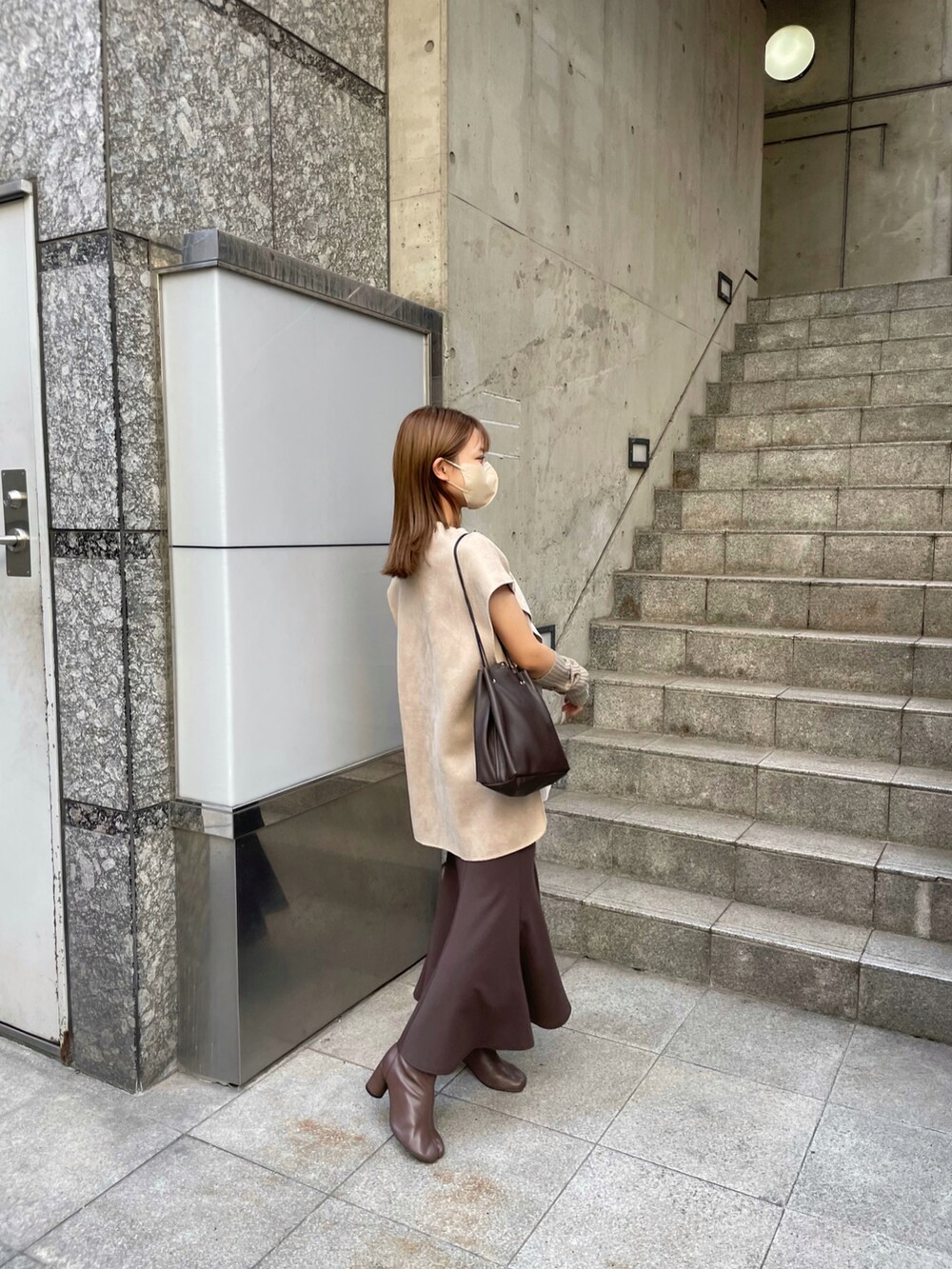 ブラウン系のブーツ、ベージュ系のベスト、ブラウン系のスカートを着用したレディースの秋コーディネートの2枚目の写真