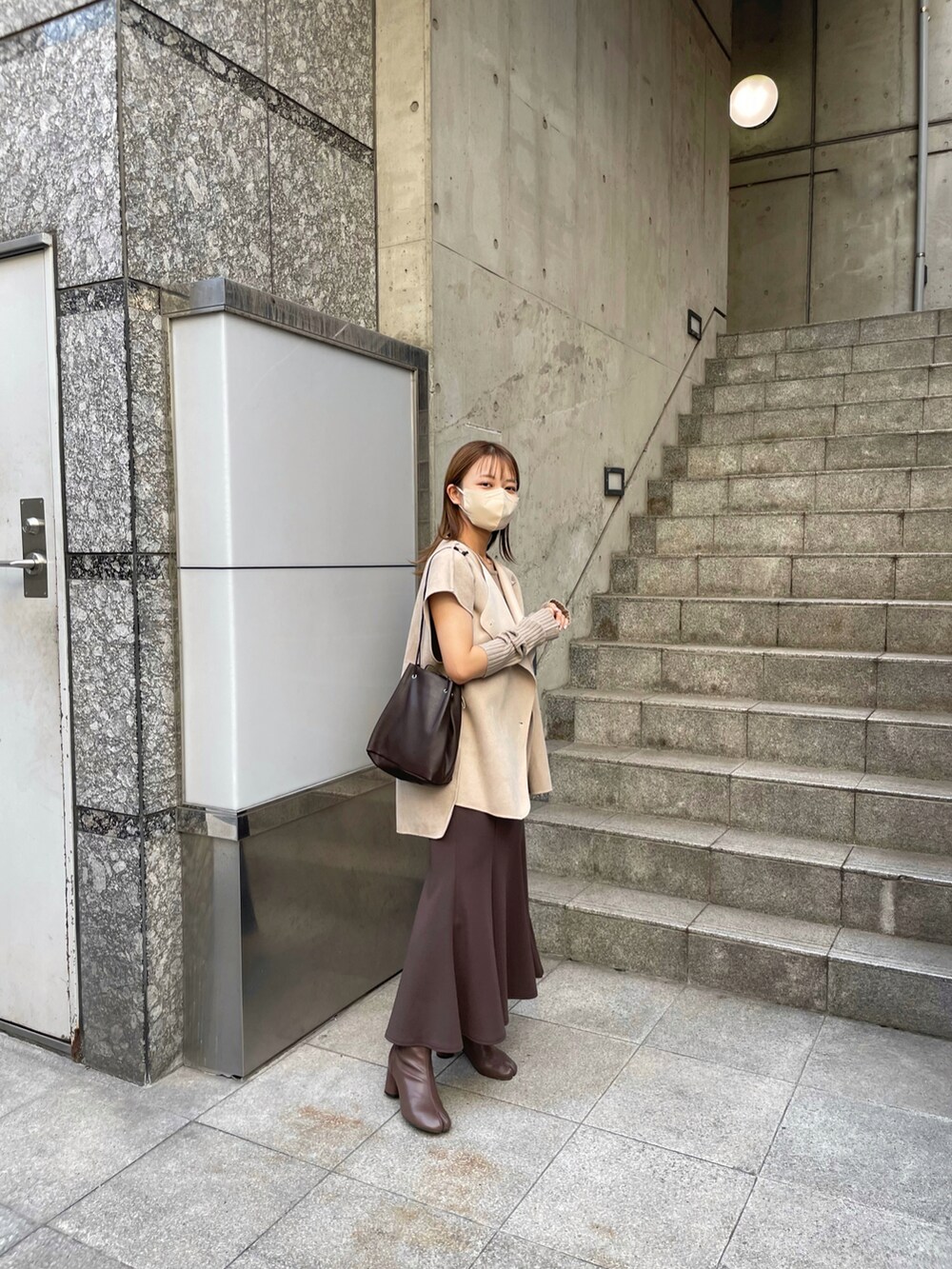 ブラウン系のブーツ、ベージュ系のベスト、ブラウン系のスカートを着用したレディースの秋コーディネートの3枚目の写真