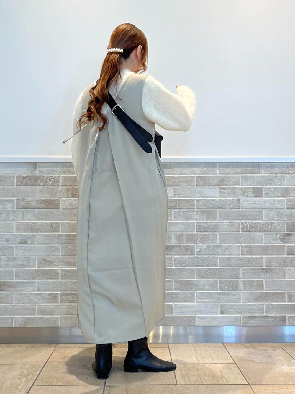 グリーン系のワンピース、ホワイト系のニット/セーター、ブラック系のブーツを着用したレディースの冬コーディネートの2枚目の写真