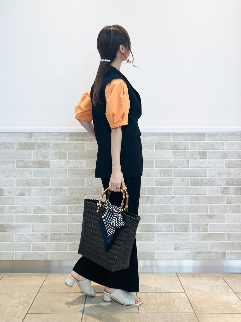 ブラック系のベスト、ブラック系のその他パンツ、ブラウン系のハンドバッグを着用したレディースの春コーディネートの5枚目の写真