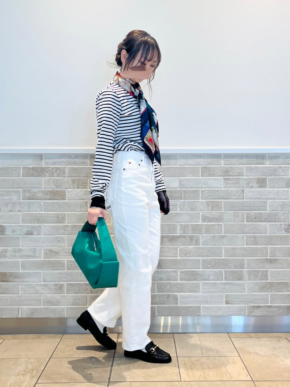 グリーン系のハンドバッグ、ブラック系のTシャツ/カットソー、ホワイト系のデニムパンツを着用したレディースの冬コーディネートの5枚目の写真