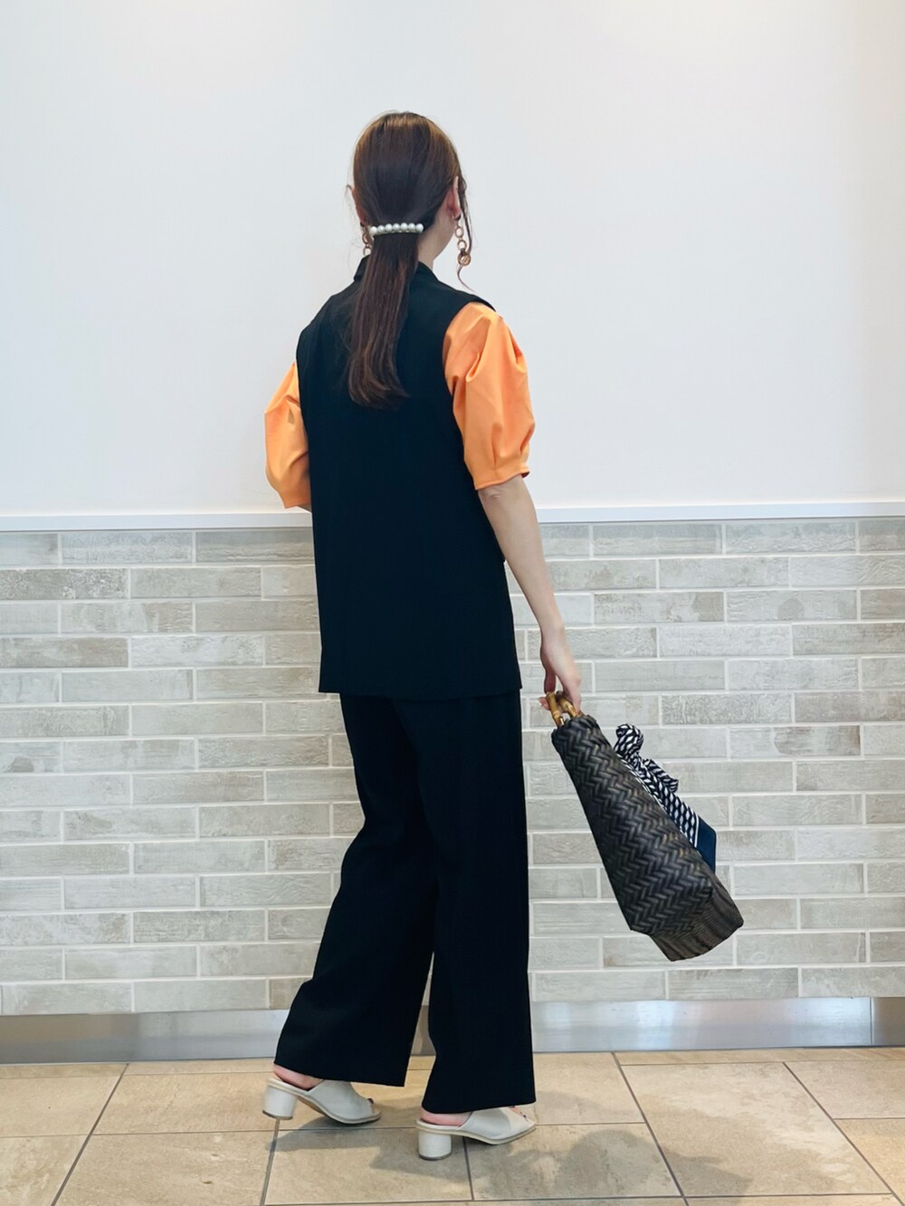 ブラック系のベスト、ブラック系のその他パンツ、ブラウン系のハンドバッグを着用したレディースの春コーディネートの3枚目の写真