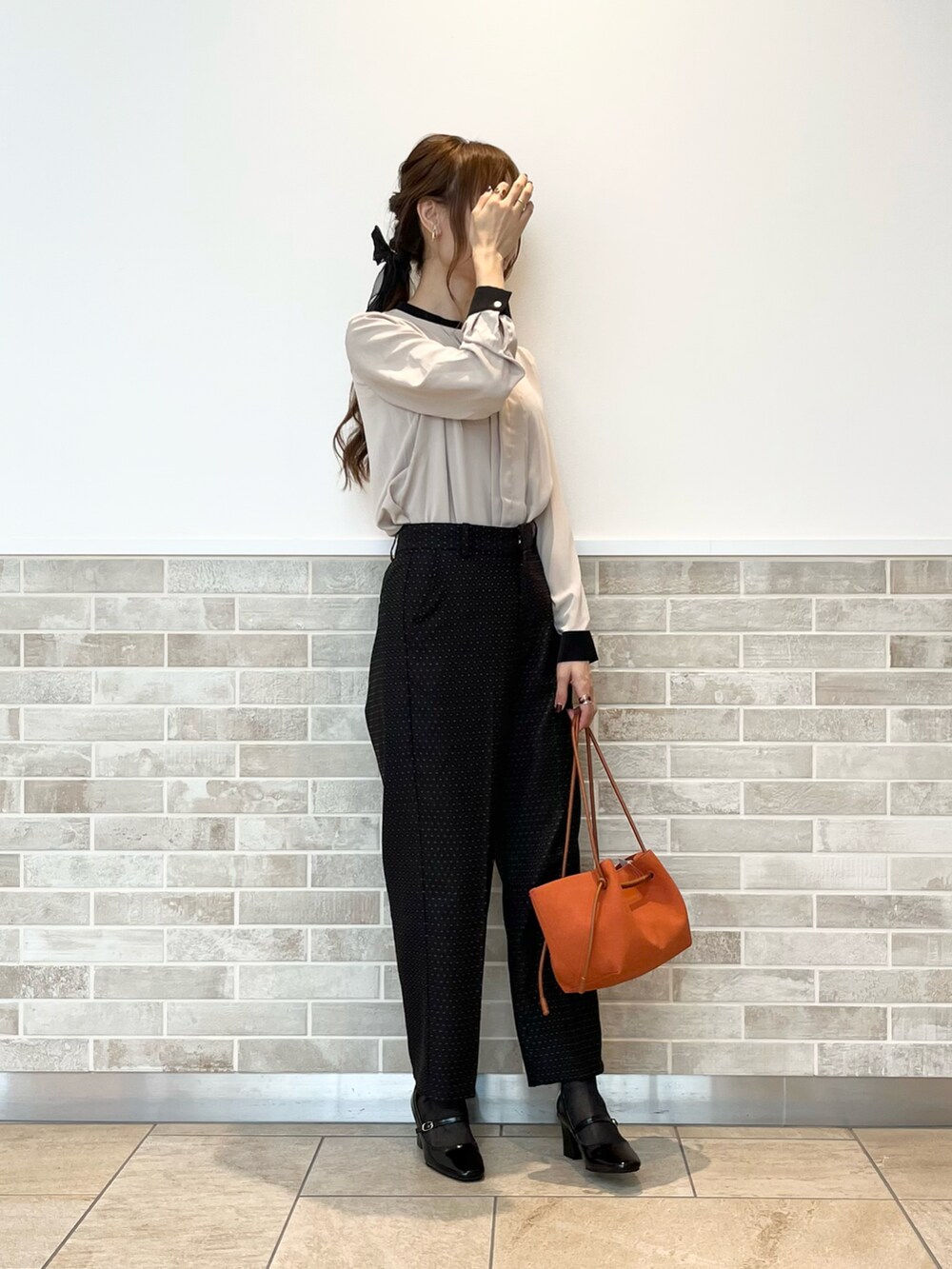 ブラック系のその他パンツ、ベージュ系のシャツ/ブラウス、オレンジ系のハンドバッグを着用したレディースの秋コーディネートの2枚目の写真