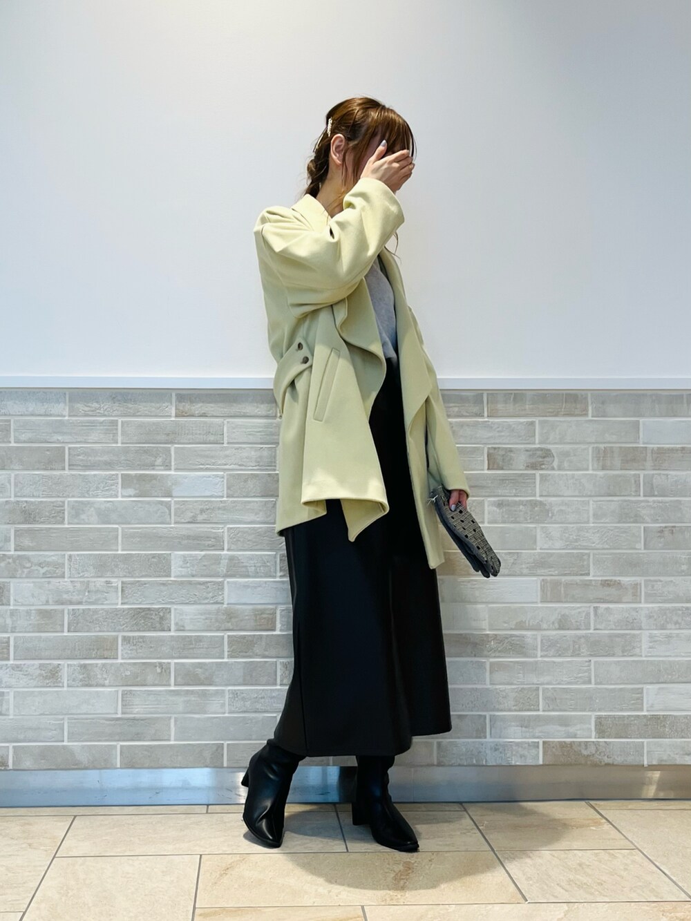 ブラック系のスカート、ブラック系のブーツ、イエロー系のその他アウターを着用したレディースの秋コーディネートの2枚目の写真