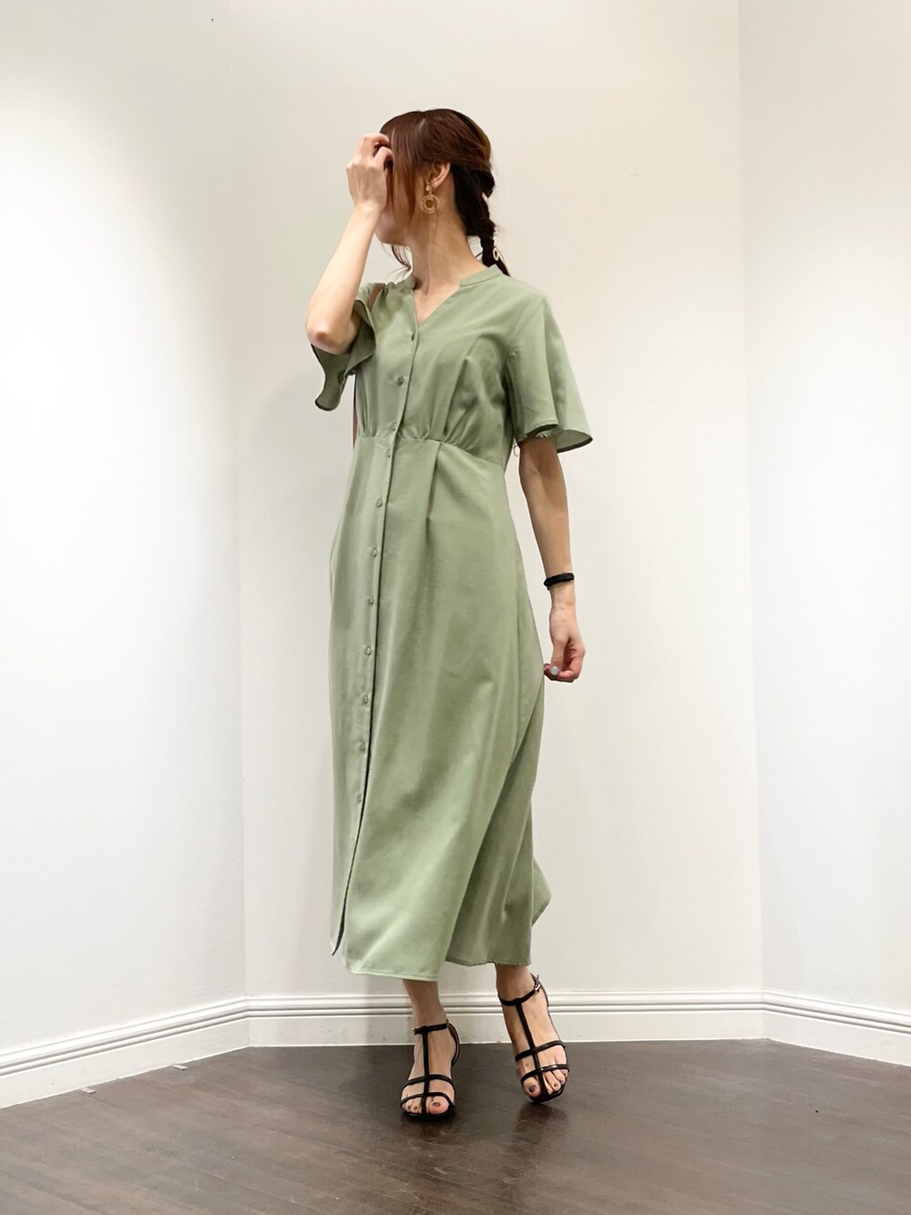 グリーン系のワンピース、ブラック系のサンダル、ブラウン系のバッグを着用したレディースの春コーディネートの3枚目の写真