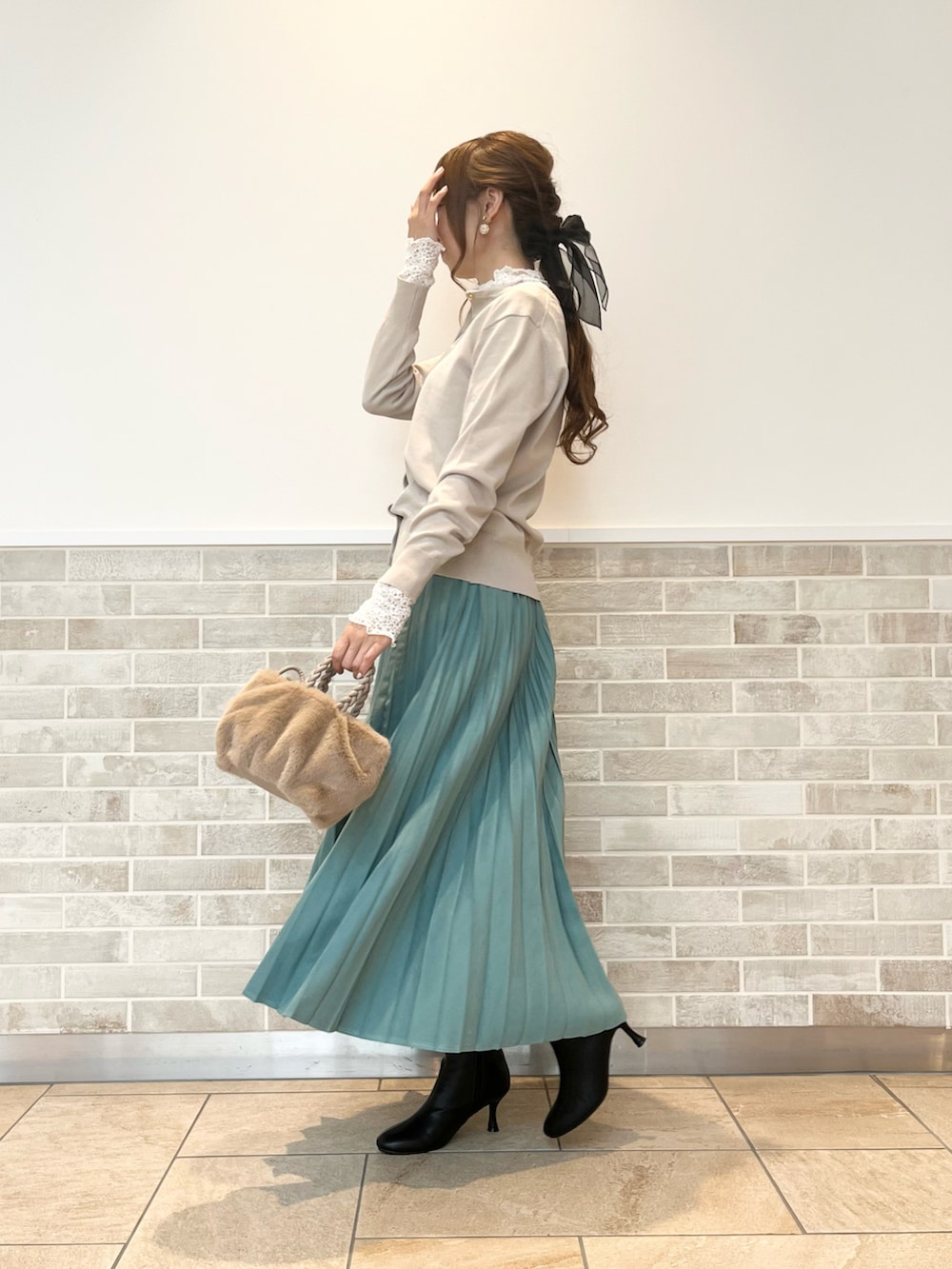 ブラック系のブーツ、グリーン系のスカート、ベージュ系のハンドバッグを着用したレディースの秋コーディネートの3枚目の写真
