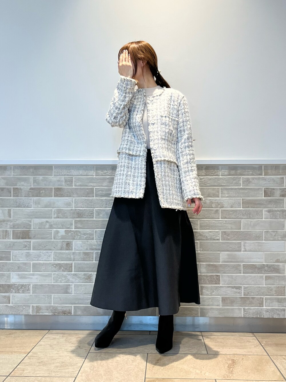 ホワイト系のノーカラージャケット、グレー系のスカート、ブラック系のブーツを着用したレディースの冬コーディネートの3枚目の写真