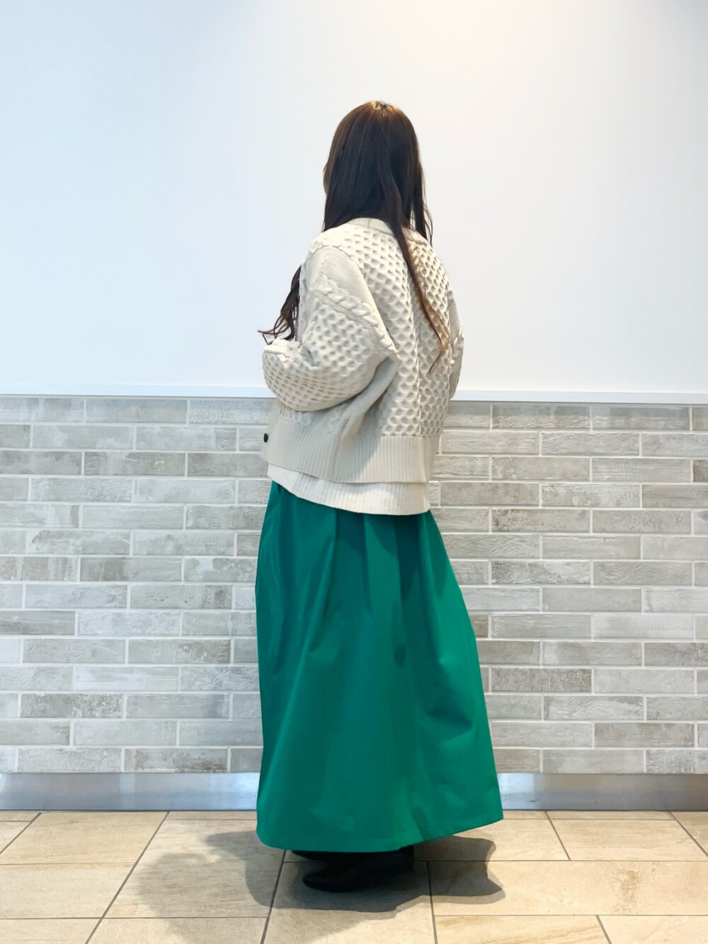 グリーン系のスカート、ホワイト系のニット/セーター、ホワイト系のカーディガン/ボレロを着用したレディースの冬コーディネートの3枚目の写真
