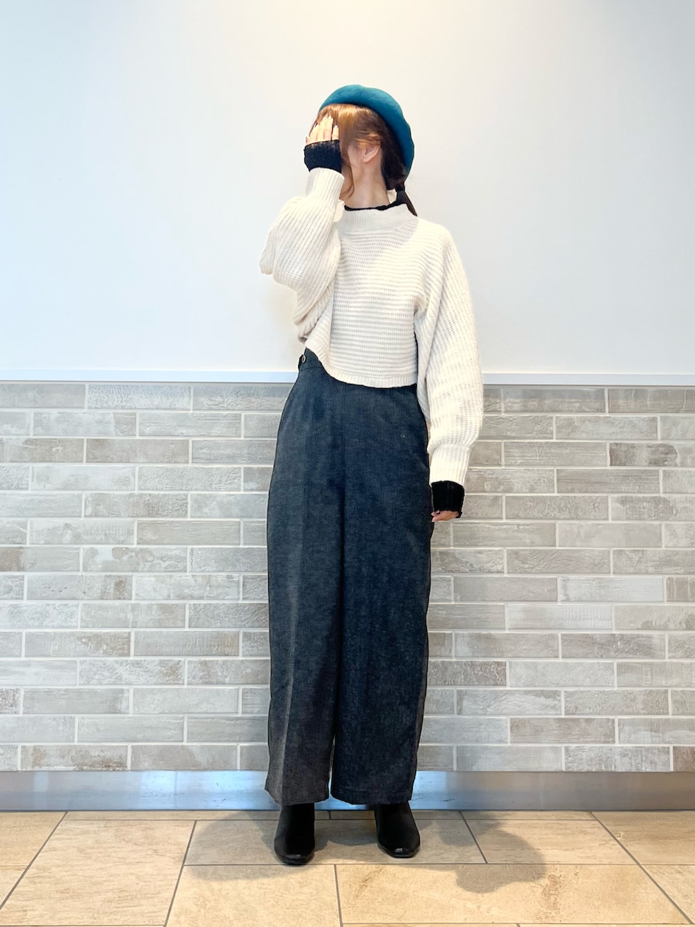 ホワイト系のニット/セーター、ブラック系のTシャツ/カットソー、グレー系のパンツを着用したレディースの冬コーディネートの2枚目の写真