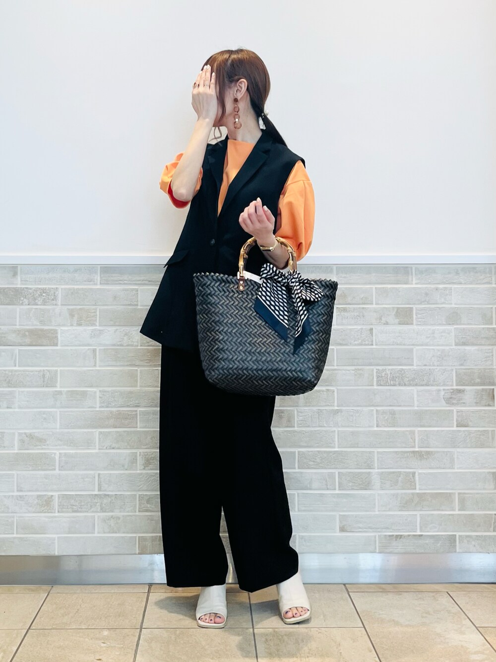 ブラック系のベスト、ブラック系のその他パンツ、ブラウン系のハンドバッグを着用したレディースの春コーディネートの2枚目の写真