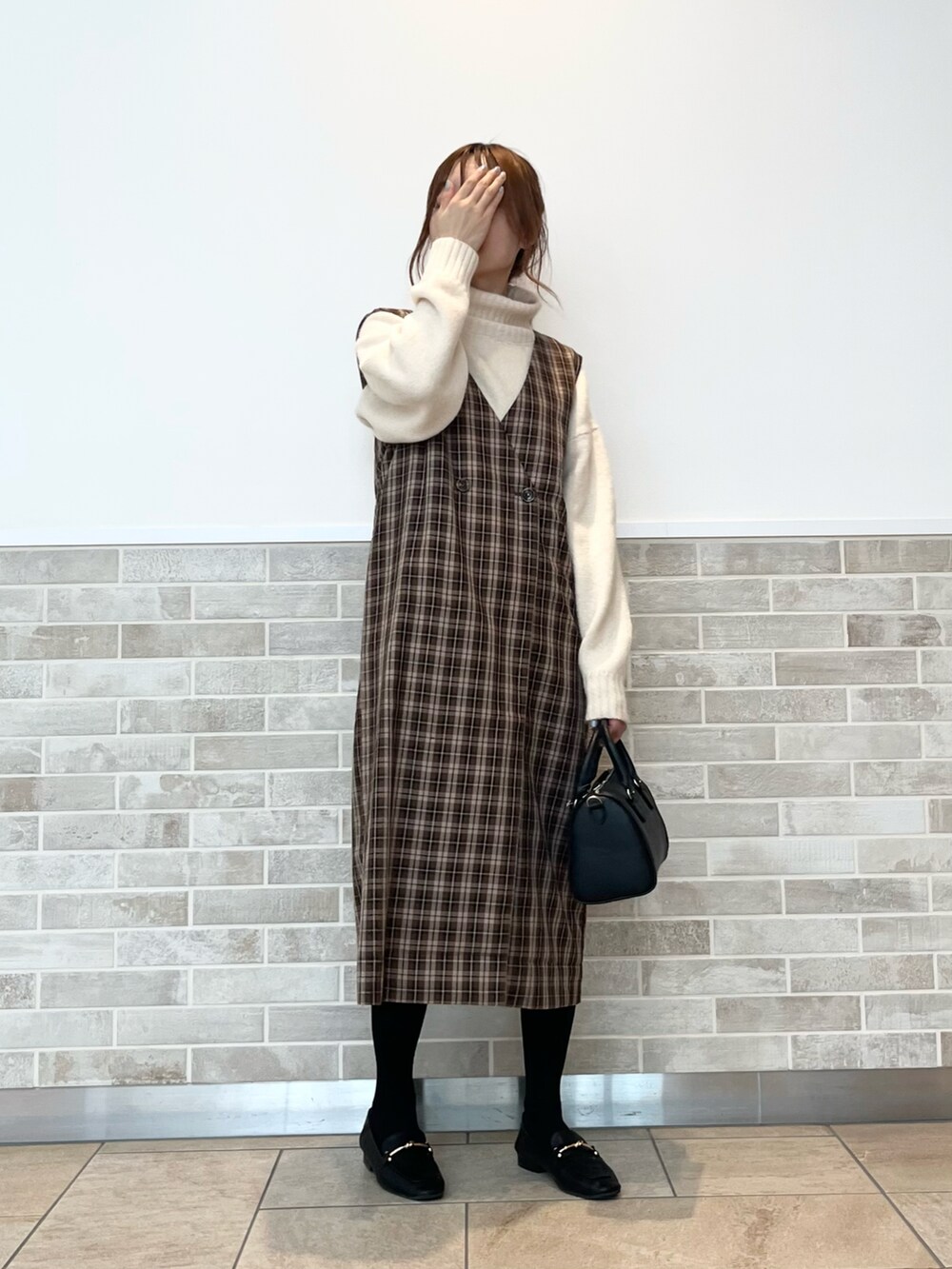 ブラウン系のワンピース、ホワイト系のニット/セーター、ブラック系のドレスシューズを着用したレディースの秋コーディネートの2枚目の写真