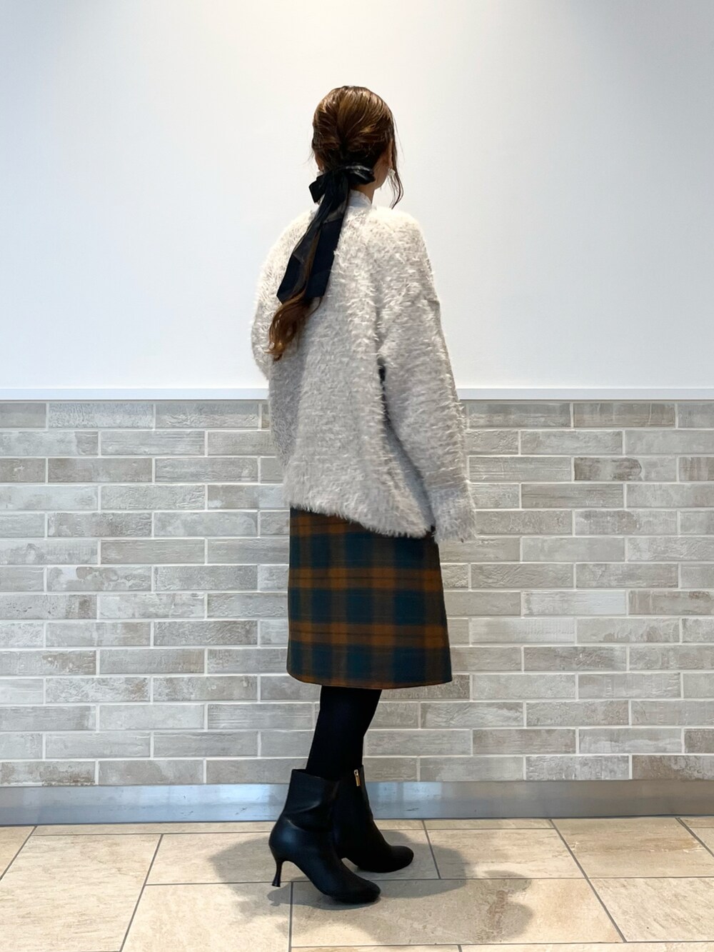 オレンジ系のスカート、ホワイト系のシャツ/ブラウス、ベージュ系のニット/セーターを着用したレディースの秋コーディネートの3枚目の写真