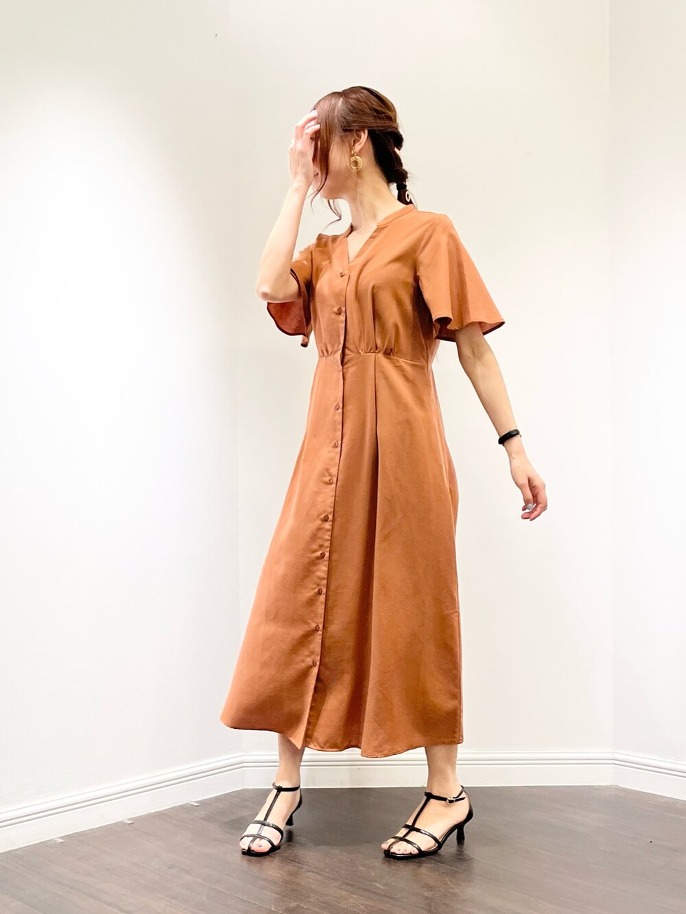 ブラウン系のワンピース、ブラック系のサンダル、ベージュ系のイヤリングを着用したレディースの春コーディネートの2枚目の写真